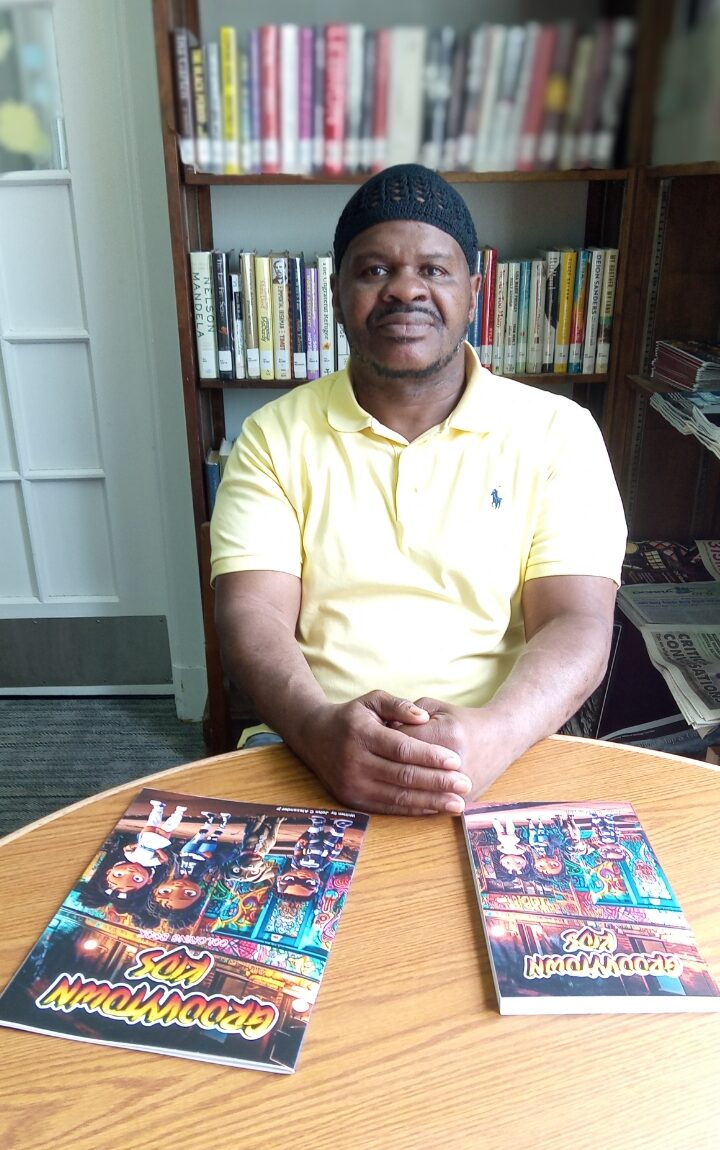 A man sits at a table with two "Groovytown Kids" books.
