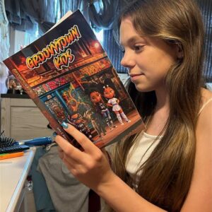 A young girl engrossed in reading a vibrant "Groovytown Kids" comic book.